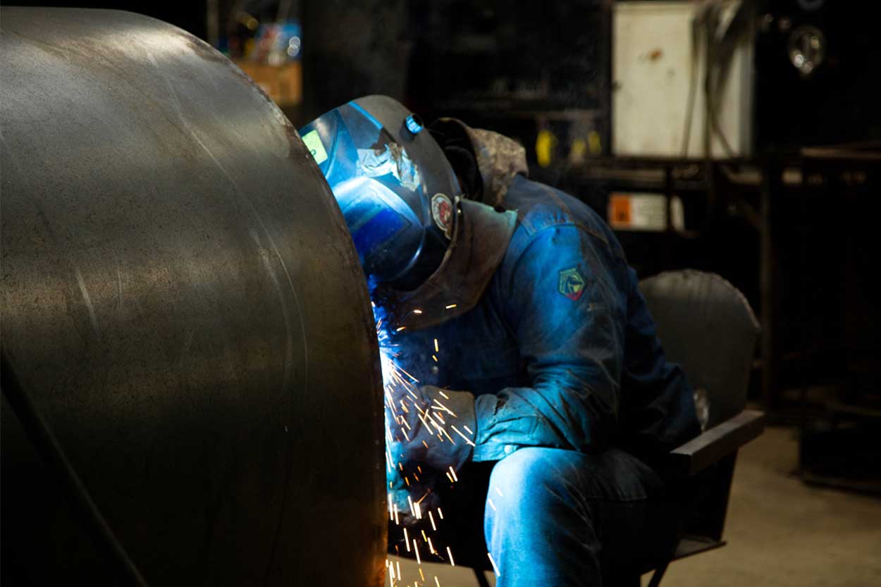 Ledwell employee welding water tank to mount on truck
